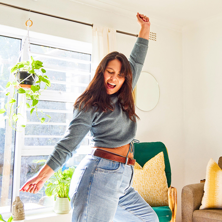 brunette lady dancing celebrating in a jumper and faded blue jeans